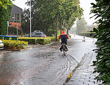 Man op fiets tijdens regenbui